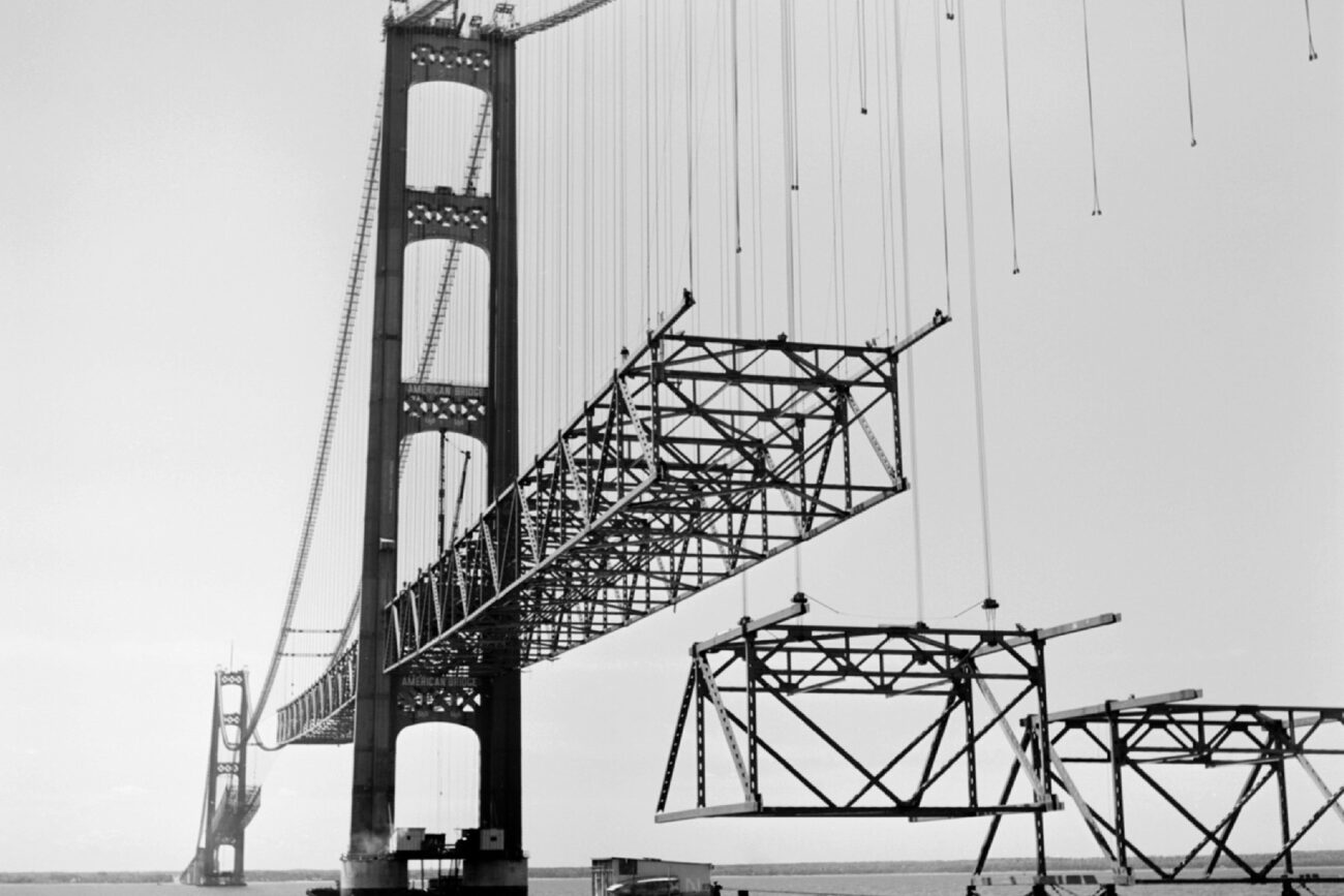 Historic Mackinac Bridge Construction images- June 20, 1957 Lifting suspended span stiffening truss unit from barge to north side of center span.. Susended Span Lifting suspended span stiffening truss unit from barge to center span.